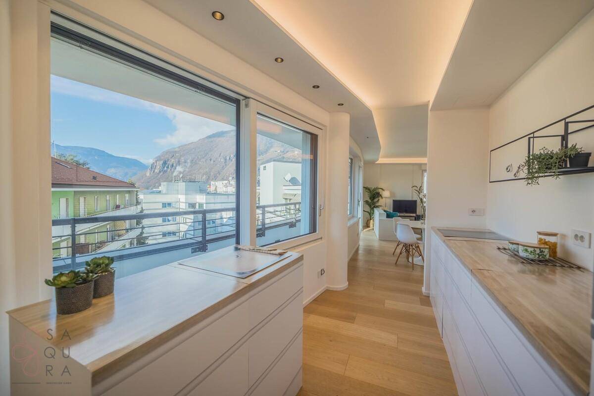 Helle Küche mit modernen Geräten, Holzboden und Panoramafenstern mit Bergblick.