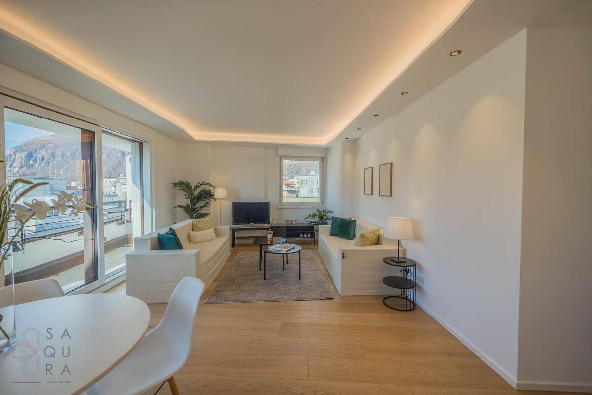 Geräumiger Wohn- und Essbereich mit Holzboden, bequemen Sofas und indirekter Deckenbeleuchtung.