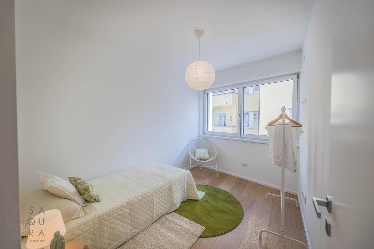 Gemütliches Schlafzimmer mit Einzelbett, Holzboden und Fenster mit Blick auf die Umgebung.