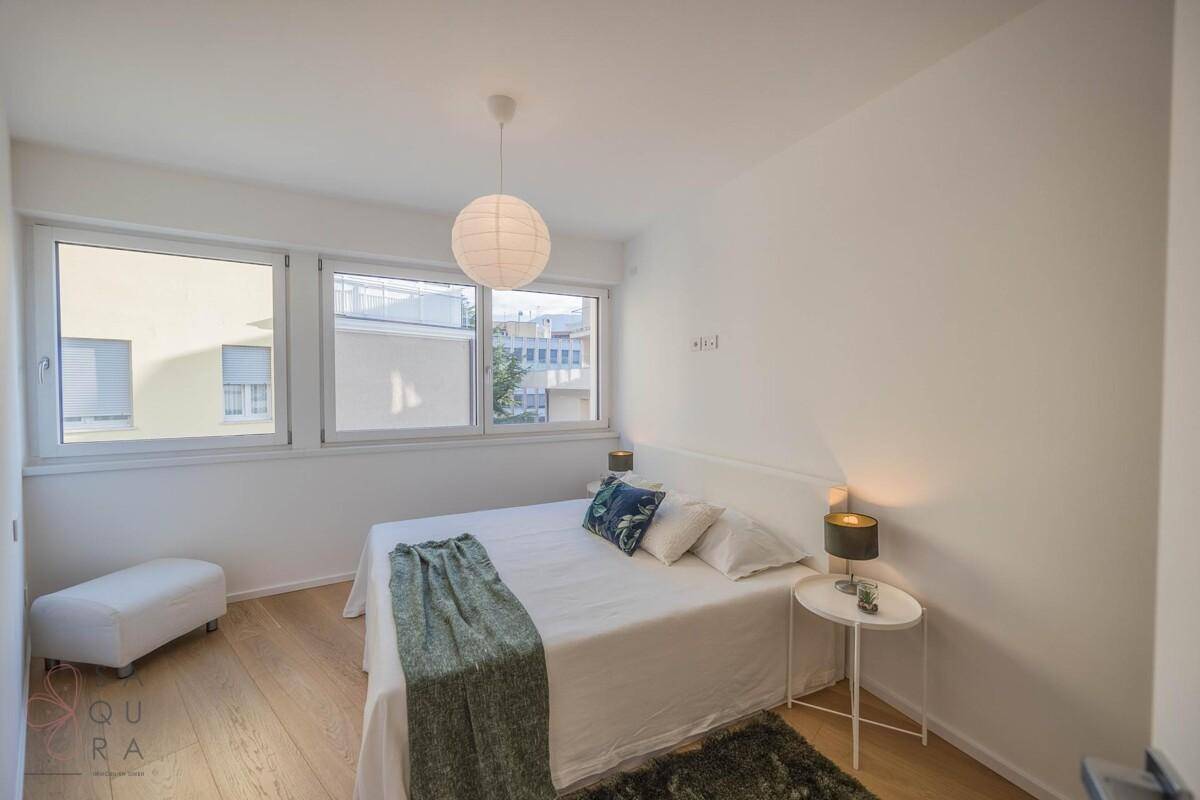 Helles Schlafzimmer mit Doppelbett, Holzboden und großen Fenstern für viel Tageslicht.