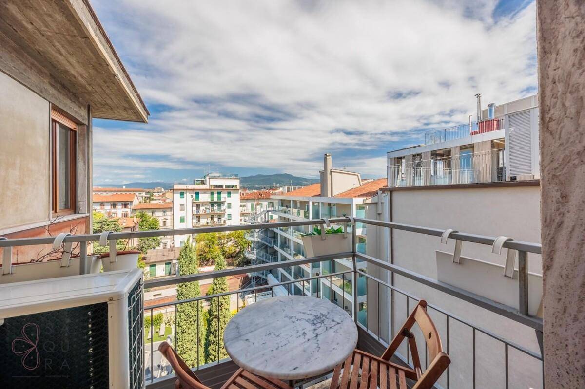 Balkon mit kleinem Tisch und Stühlen bietet einen weiten Blick über die Stadt und die Berge.