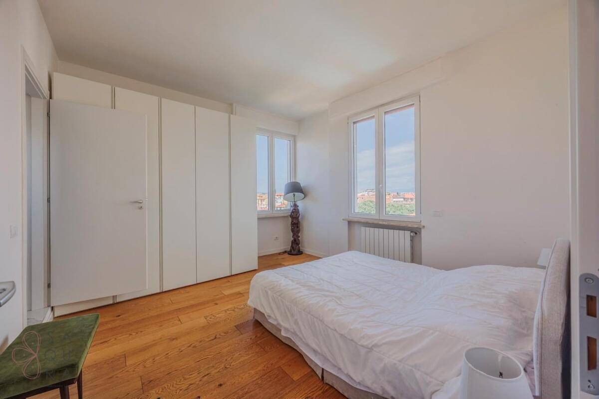 Helles Schlafzimmer mit großem Bett, integrierten Kleiderschränken und Holzboden.