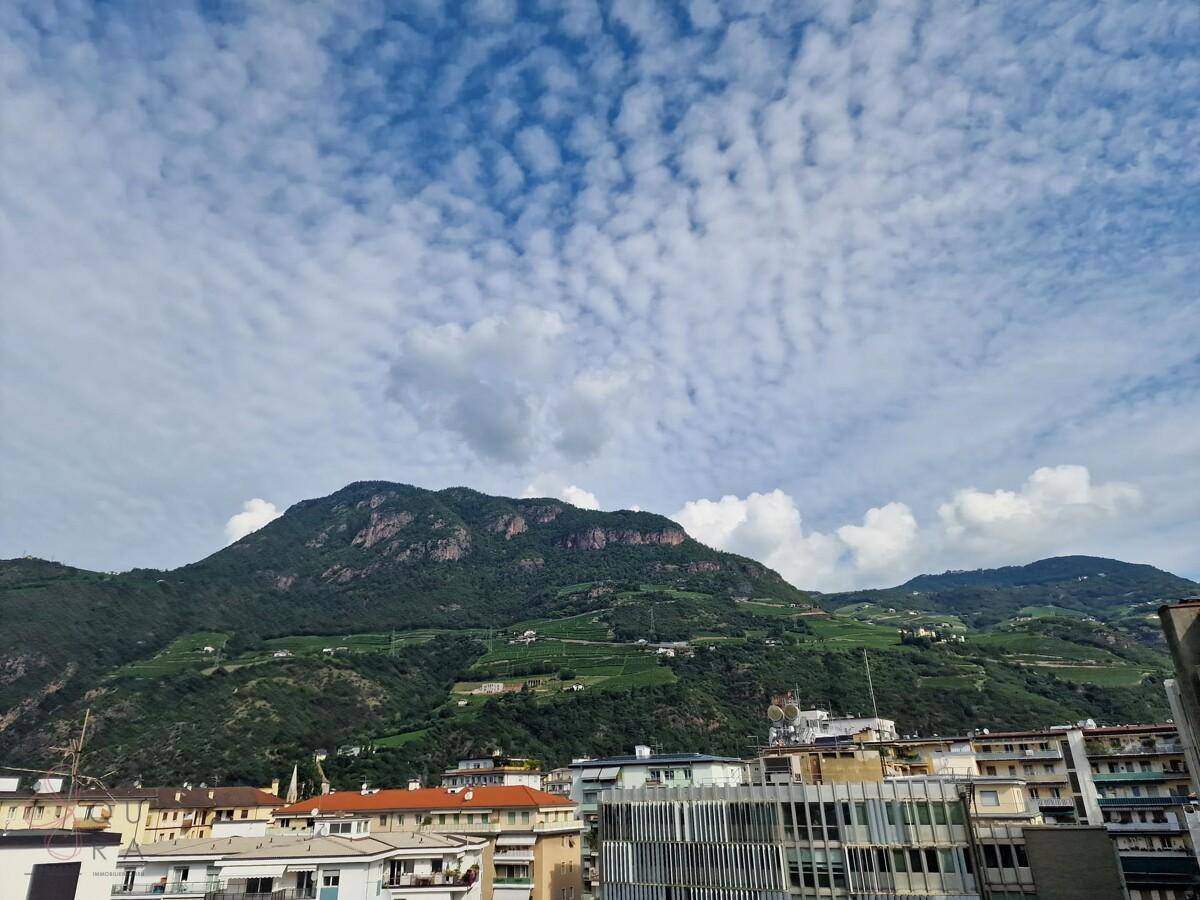 Panoramablick auf die majestätischen Berge und die darunter liegende Stadtlandschaft unter blauem Himmel.