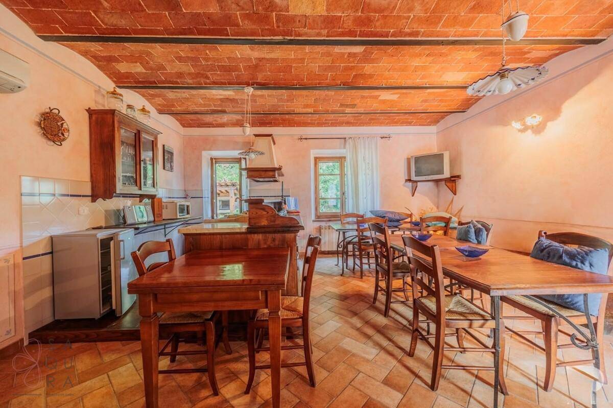 Rustikale Wohnküche mit Holztischen, Terrakottafliesen und traditioneller Einrichtung.