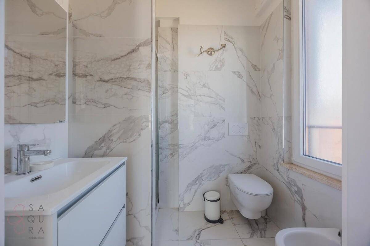 Modernes Badezimmer mit eleganten Marmorfliesen, Dusche und wandhängendem WC.
