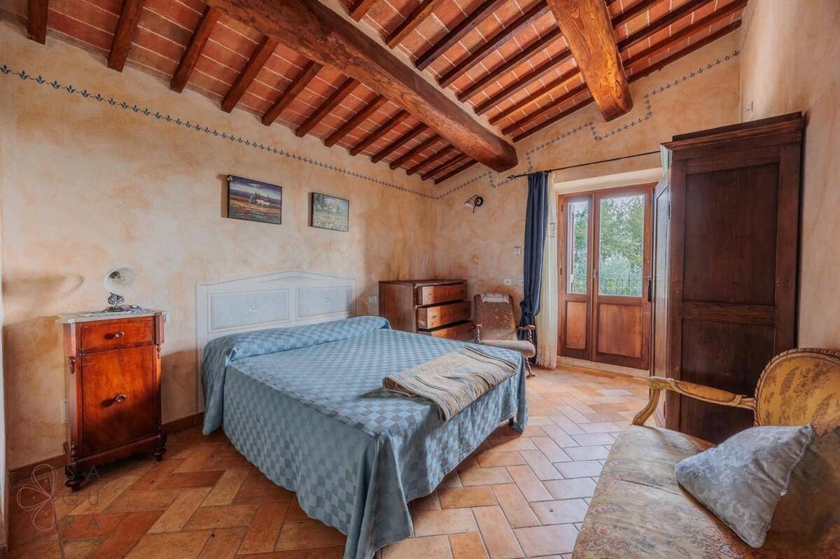Gemütliches Schlafzimmer mit Terrakottafliesen, Holzbalken und Zugang zum Balkon.
