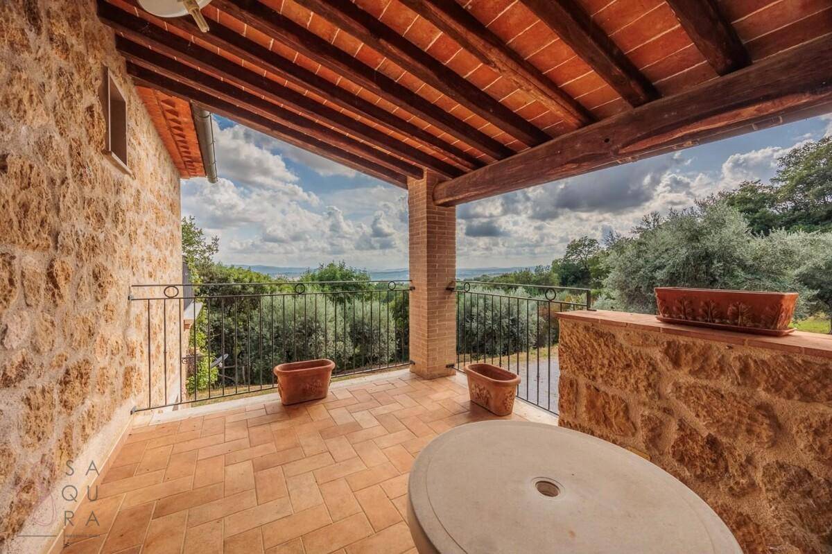 Überdachter Balkon mit Terrakottafliesen und weitem Blick über die grüne Landschaft.