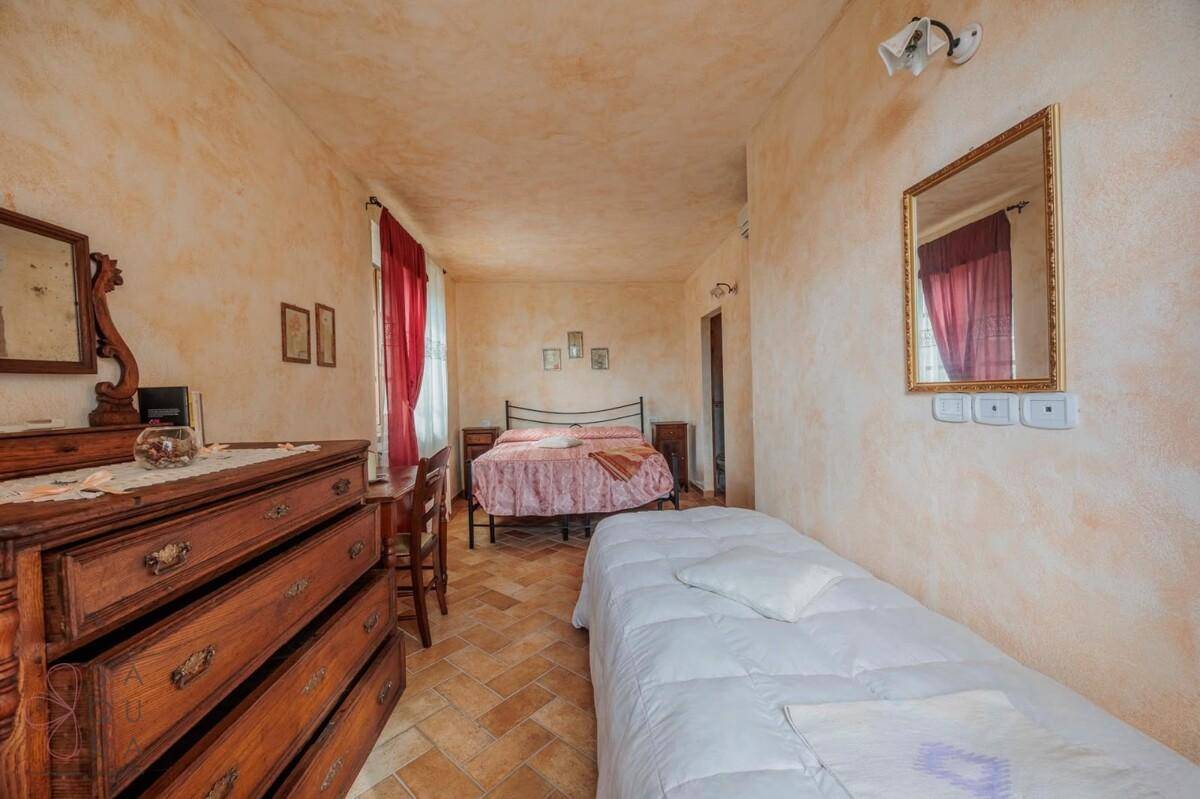 Geräumiges Schlafzimmer mit zwei Betten, Terrakottafliesen und traditionellen Holzmöbeln.