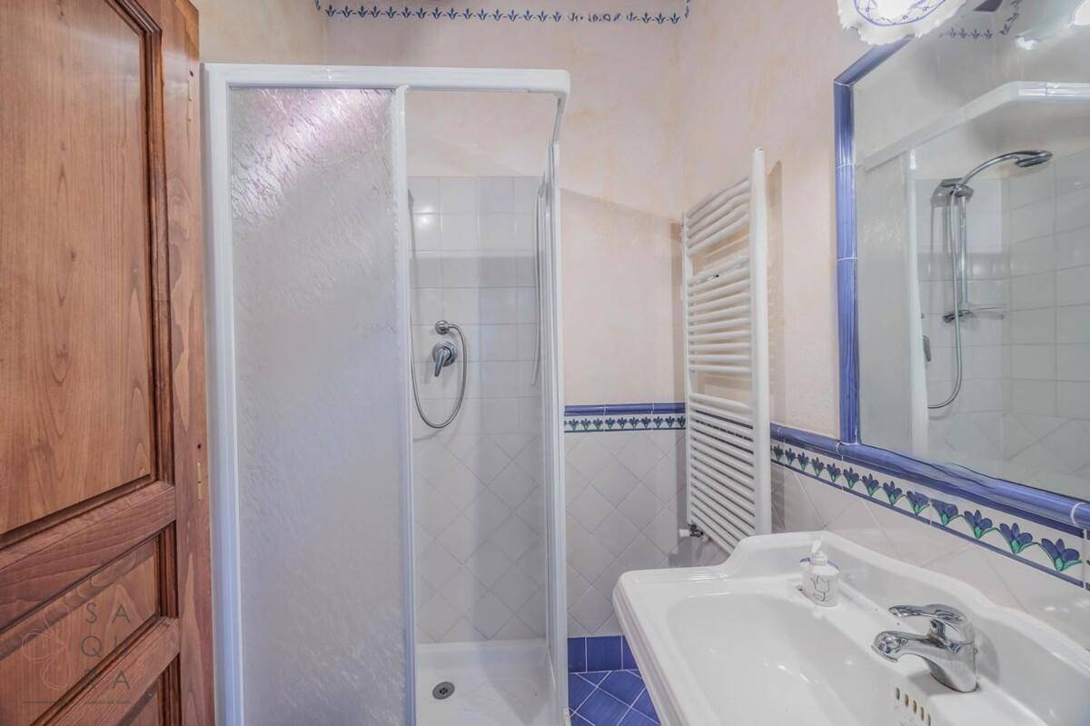 Helles Badezimmer mit Dusche, Waschbecken und beheiztem Handtuchhalter, in blau-weißem Design.
