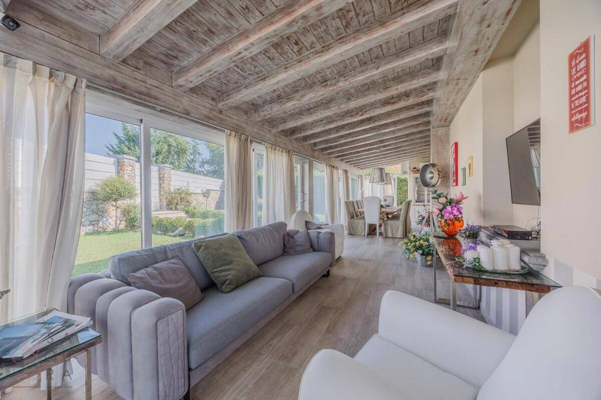Gemütliches Wohnzimmer mit Holzbalkendecke, bequemen Sofas und Blick in den Garten.