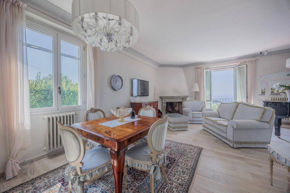 Eleganter Wohn-Essbereich mit Kamin, Kronleuchter und großen Fenstern mit Fernblick.