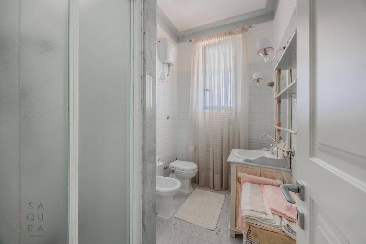 Helles Badezimmer mit Dusche, WC und Fenster, ausgestattet mit einem Waschtisch.