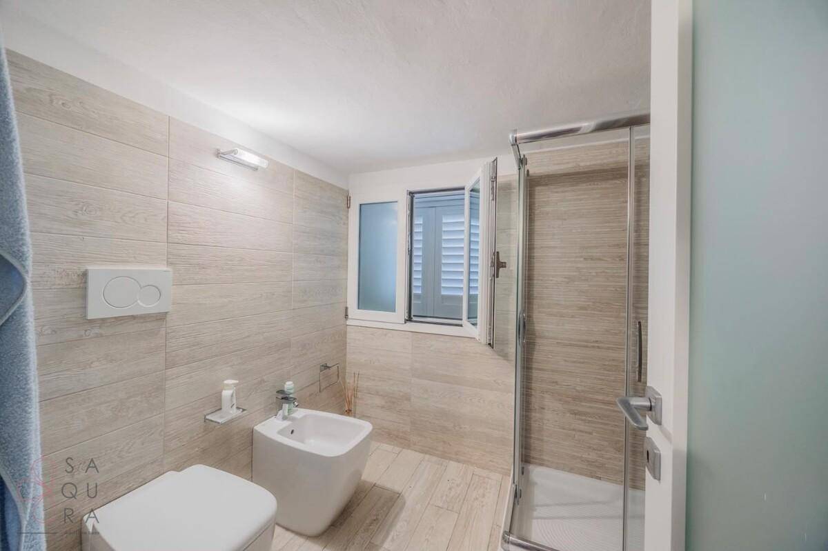 Modernes Badezimmer mit begehbarer Dusche, Bidet und Fenster für Tageslicht.