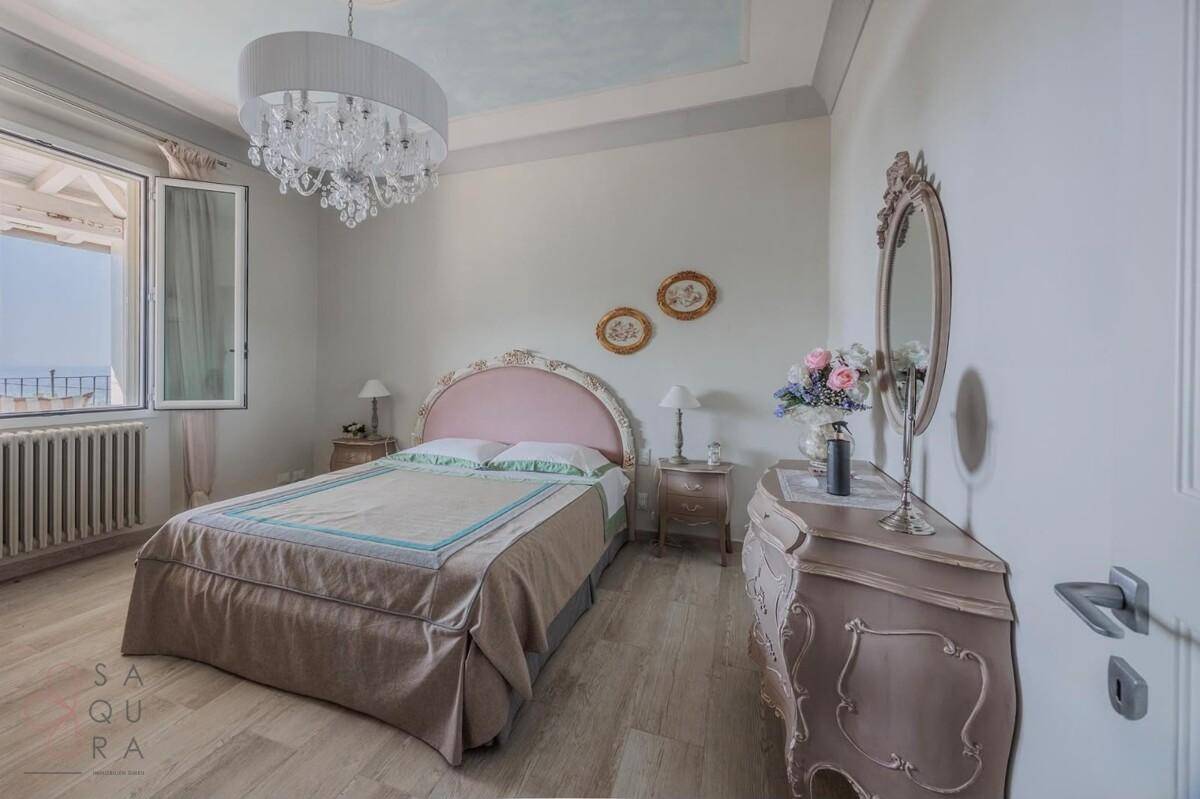 Helles Schlafzimmer mit elegantem Bett, Kommode und Fenster mit weitem Ausblick.