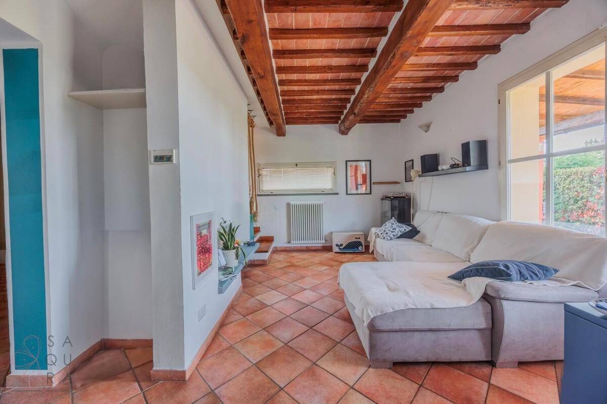 Geräumiges Wohnzimmer mit Terrakottaboden, freiliegenden Holzbalken und einem großen Sofa.