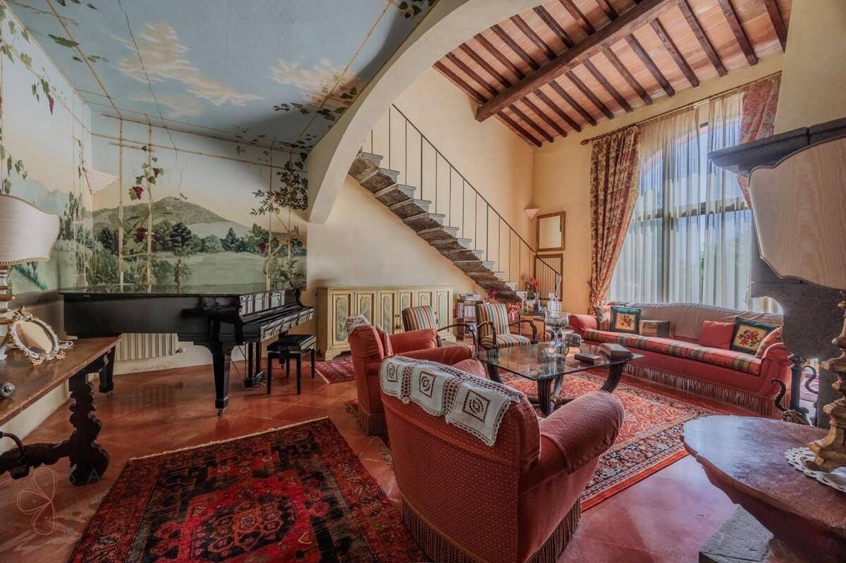Elegantes Wohnzimmer mit Terrakottaboden, freiliegenden Holzbalken und einer kunstvollen Wandmalerei.
