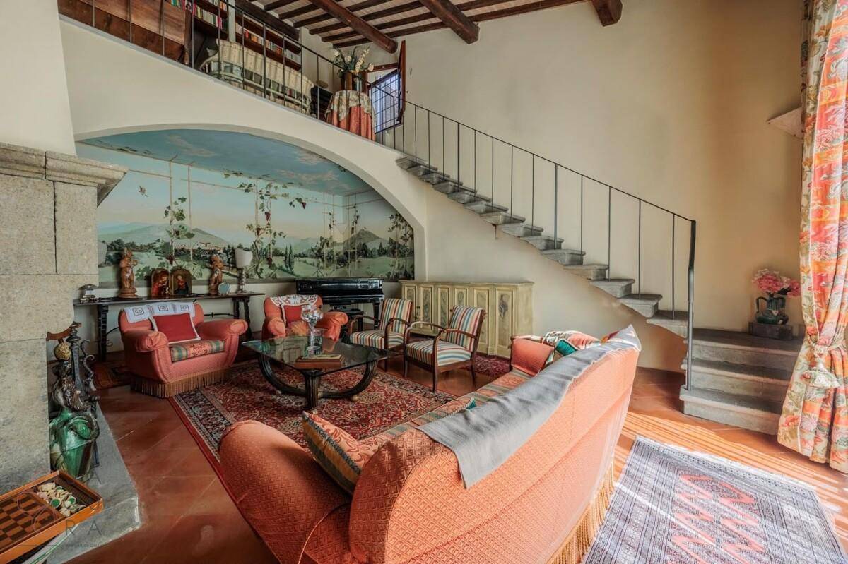 Großzügiges Wohnzimmer mit traditionellem Kamin, Terrakottaboden und einer Treppe zur Galerie.
