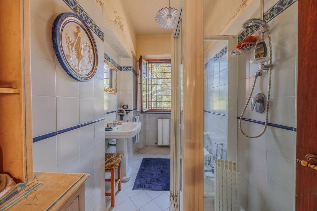 Funktionales Badezimmer mit Duschkabine, weißen Fliesen und einem Fenster für natürliche Belüftung.