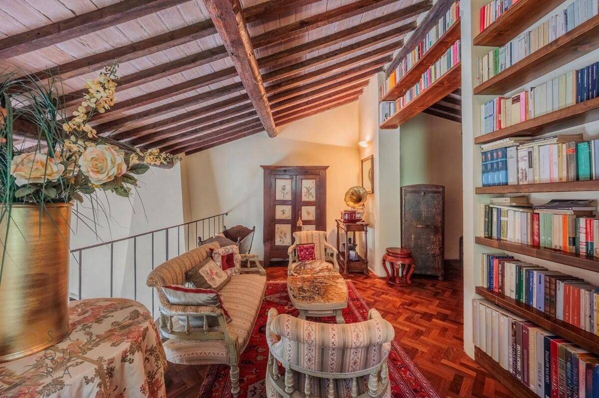 Gemütliche Galerie mit vielen Büchern, Holzbalkendecke und traditionellem Fischgrätparkett.