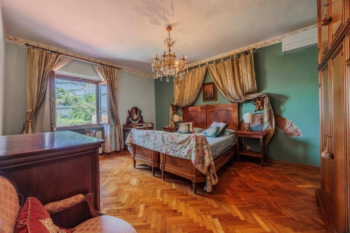 Klassisches Schlafzimmer mit Fischgrätparkett, grünen Wänden und einem großen Holzbett.