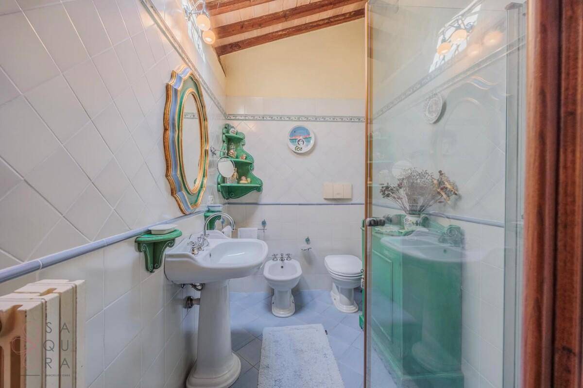 Helles Badezimmer mit weißen Fliesen, freistehendem Waschbecken und einem Bidet.