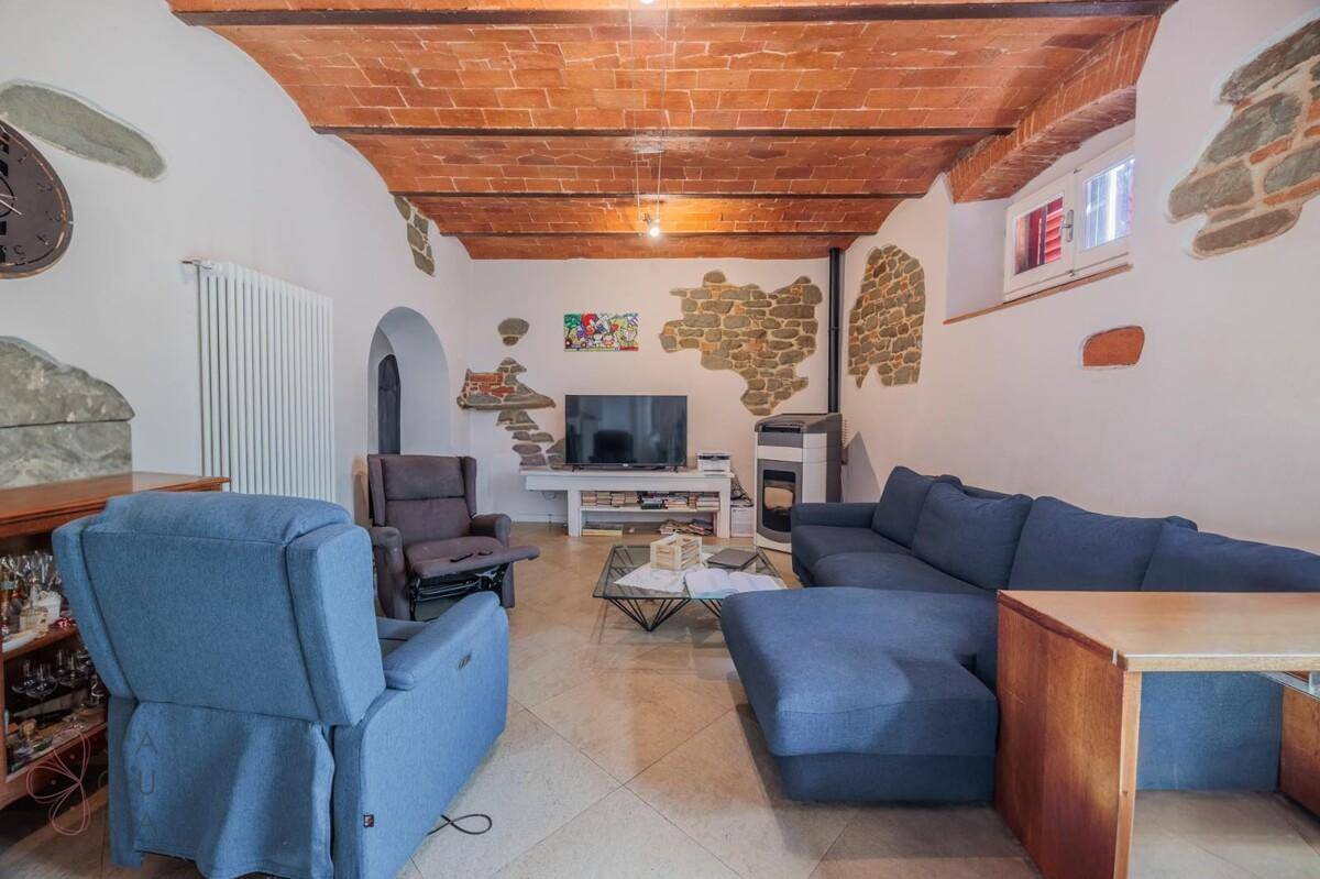 Gemütliches Wohnzimmer mit blauer Couch, freiliegenden Ziegeldecken und rustikalen Steinakzenten.