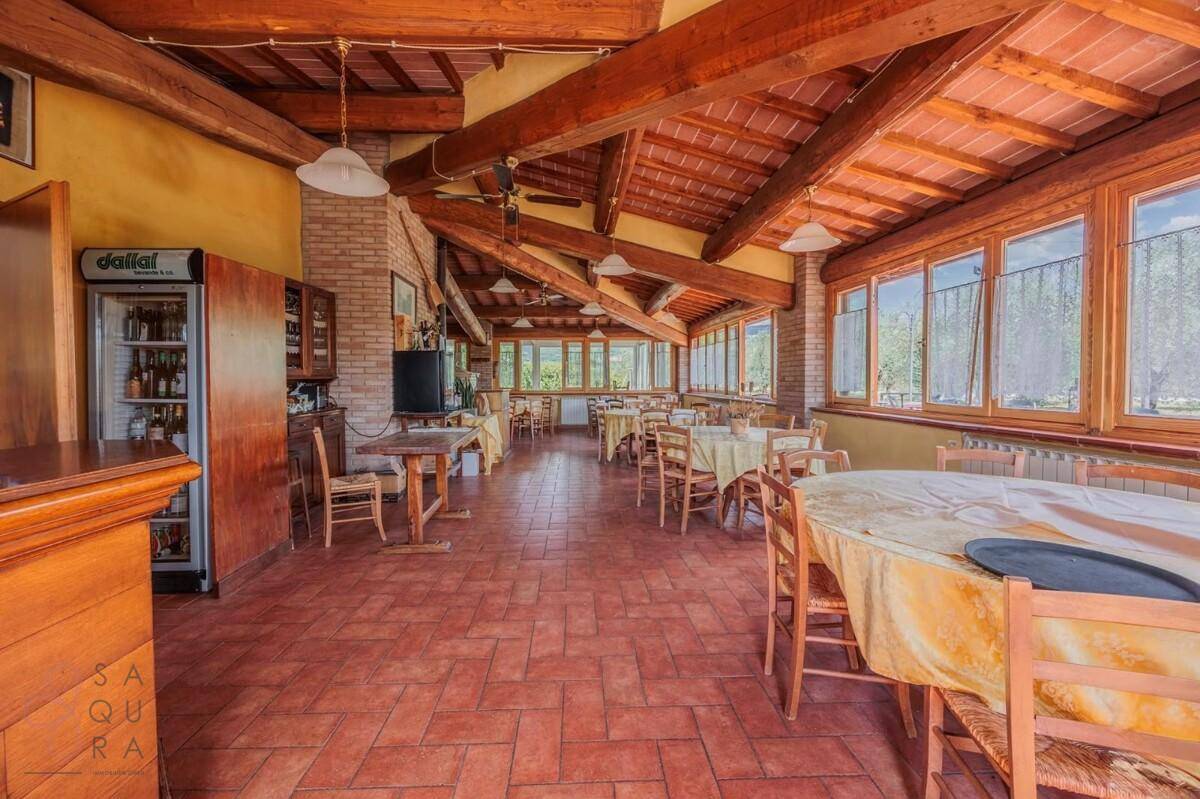 Geräumiger Speisesaal mit Holzbalkendecke, Terrakottaboden und großen Fenstern mit Ausblick.