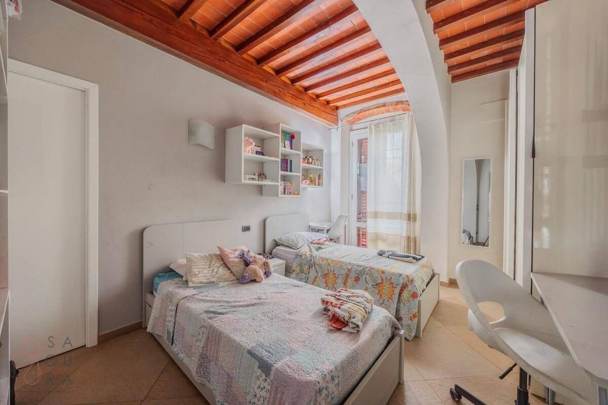 Helles Schlafzimmer mit zwei Einzelbetten, weißen Möbeln und Zugang zu einem kleinen Balkon.