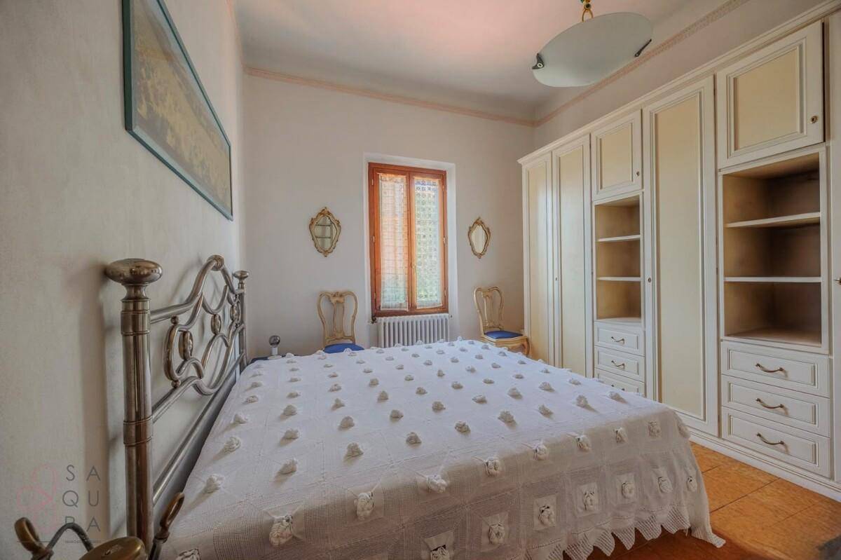Helles Schlafzimmer mit großem Bett, Einbauschränken und Terrakotta-Fliesenboden.
