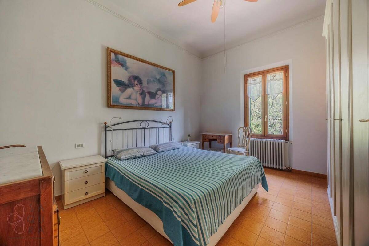 Schlafzimmer mit Doppelbett, weißem Kleiderschrank und Terrakotta-Fliesenboden.