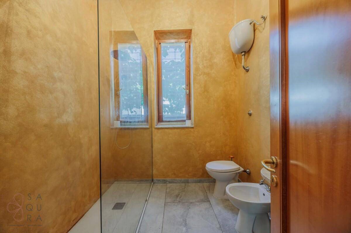 Badezimmer mit Duschkabine, Toilette und Bidet, Wände in warmem Ockerton.