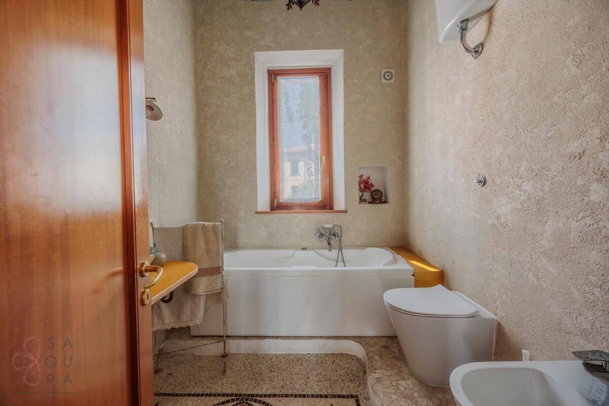 Badezimmer mit Badewanne, Bidet und strukturierten Wänden in hellem Beigeton.