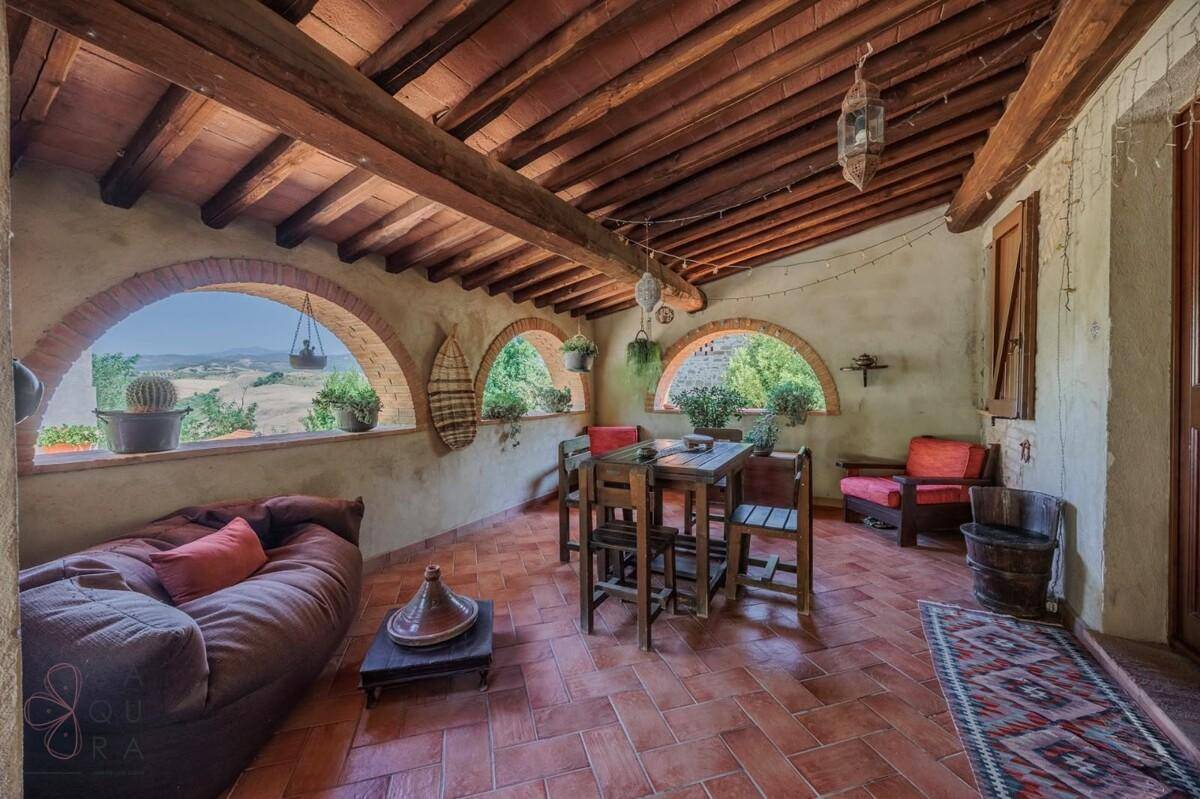 Gemütliche Loggia mit Holzbalkendecke und Rundbogenfenstern, bietet einen malerischen Blick auf die Landschaft.
