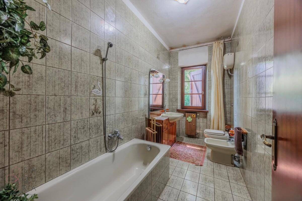Traditionelles Badezimmer mit grünen Fliesen und Badewanne, ausgestattet mit Bidet und Fenster.