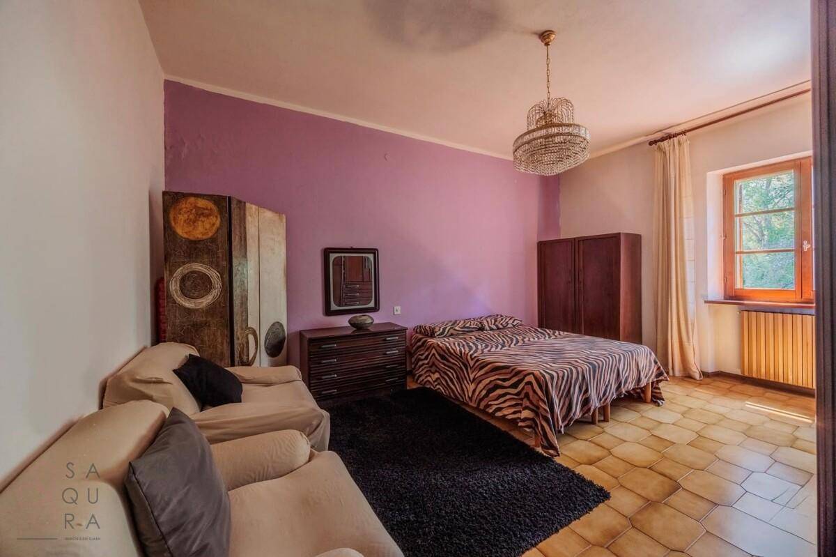 Schlafzimmer mit lila Wänden und gemustertem Bett, ausgestattet mit einem Kronleuchter.