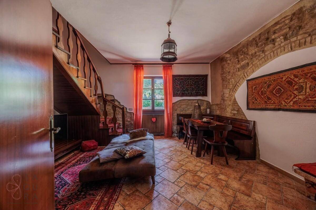 Rustikaler Wohn- und Essbereich mit Terrakottafliesen und Holztreppe, gemütlich eingerichtet.