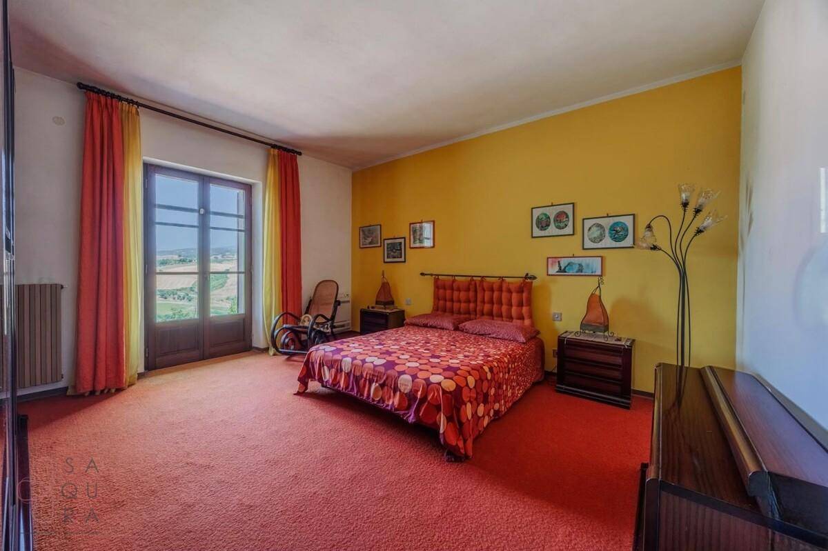 Helles Schlafzimmer mit gelben Wänden und rotem Teppichboden, bietet Zugang zu einem Balkon.