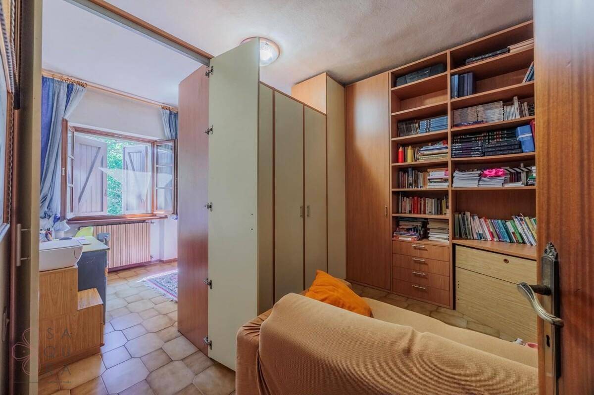 Kleines Schlafzimmer mit integrierten Schränken und Bücherregal, bietet einen Blick ins Grüne.