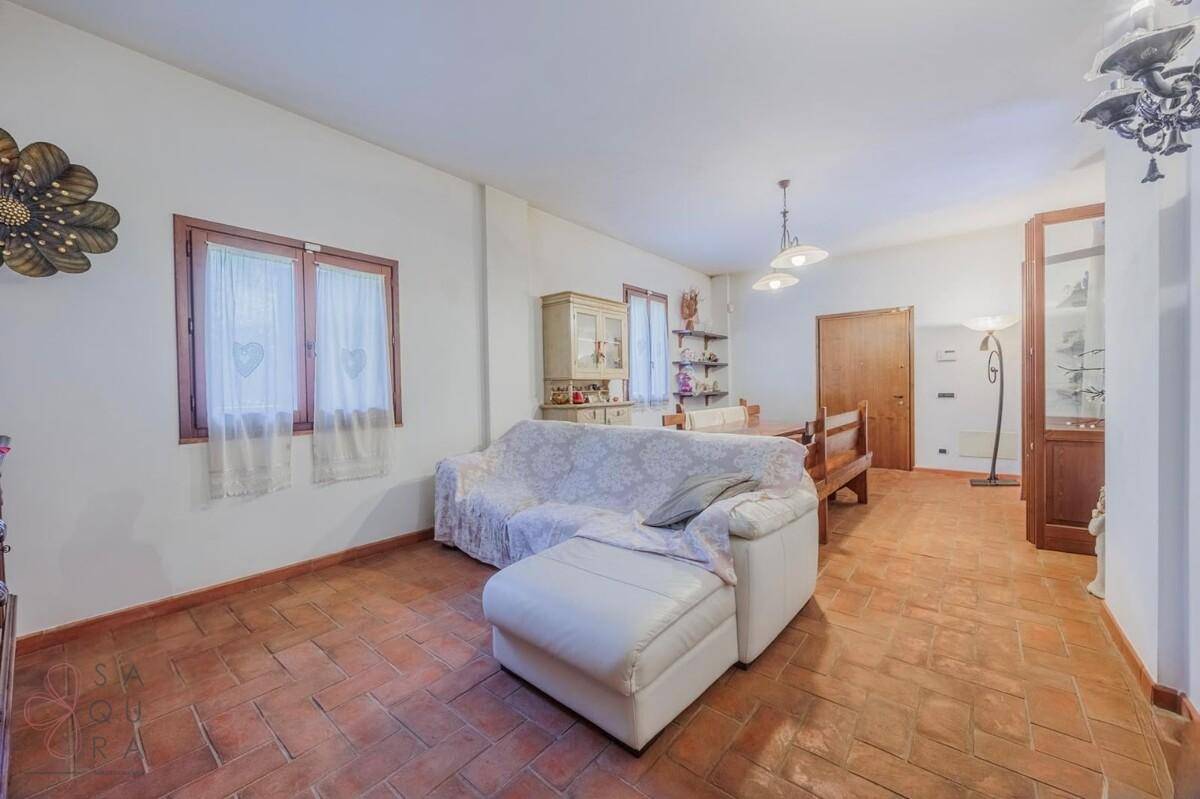 Gemütliches Wohnzimmer mit weißem Sofa, Terrakottaboden und traditionellen Holzmöbeln.