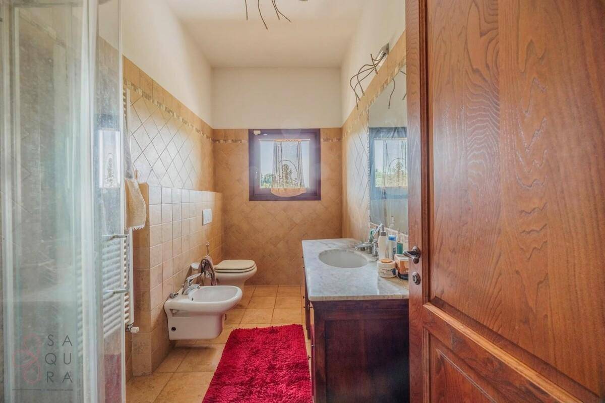 Geräumiges Badezimmer mit Dusche, WC, Bidet und Doppelwaschbecken mit Marmorplatte und Terrakottaboden.
