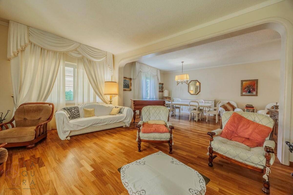 Geräumiger Wohn-Essbereich mit Holzboden, eleganten Möbeln und viel Tageslicht.