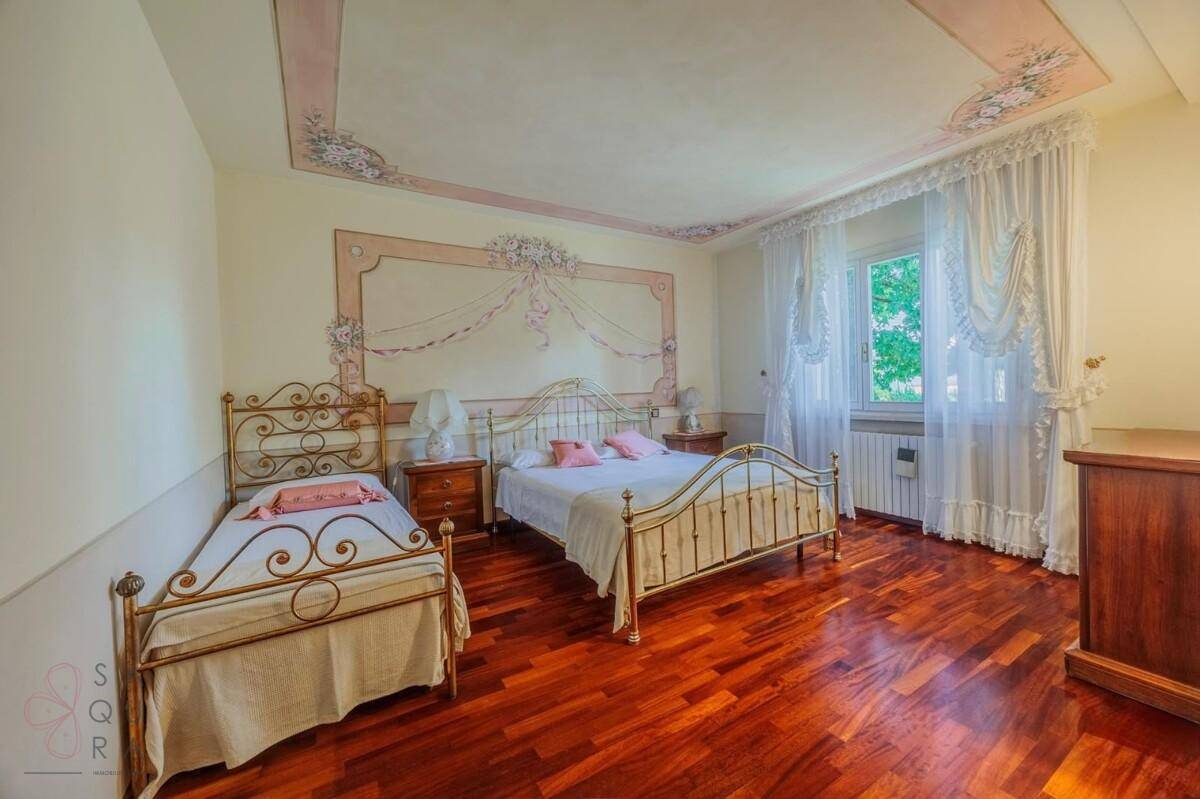 Geräumiges Schlafzimmer mit Holzboden, zwei Betten und einer kunstvoll bemalten Decke.