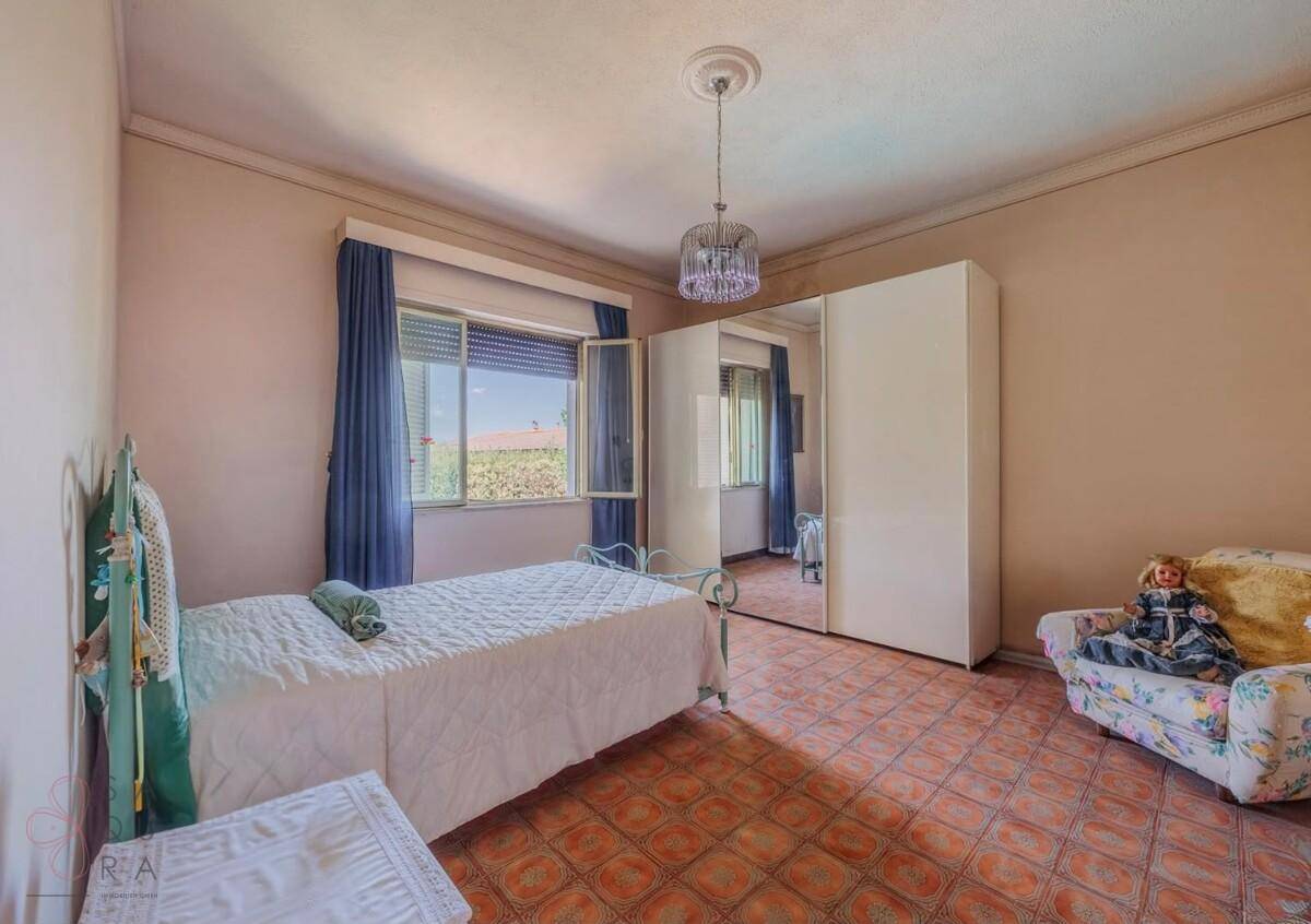 Schlafzimmer mit Terrakotta-Fliesenboden, Einzelbett und einem großen Spiegelschrank.