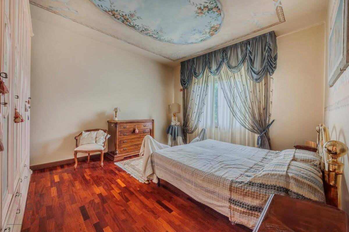 Elegantes Schlafzimmer mit Holzboden, kunstvoll bemalter Decke und schweren Vorhängen.