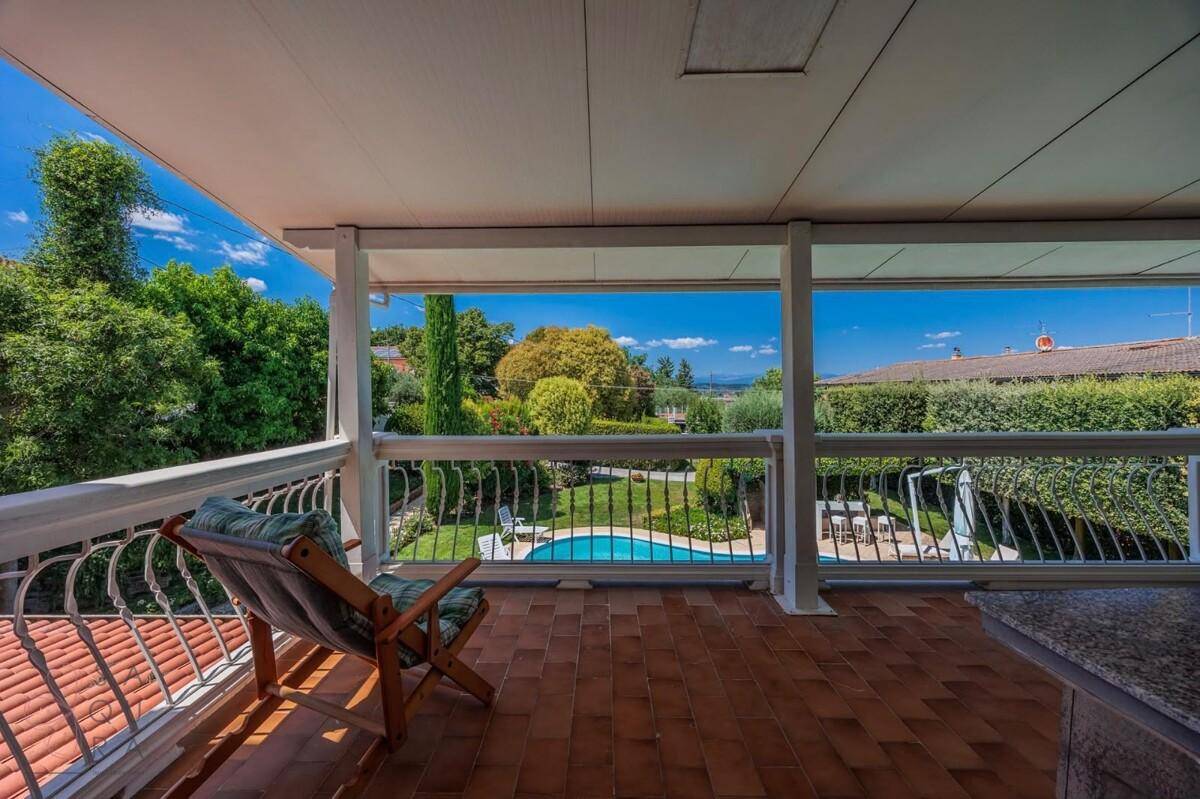 Überdachter Balkon mit Terrakotta-Boden und weitem Blick auf den Pool und den Garten.