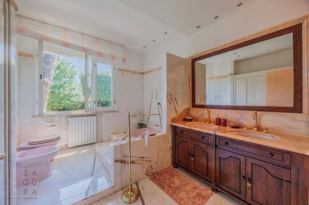 Luxuriöses Badezimmer mit Marmoroberflächen, Doppelwaschbecken und einer Badewanne.