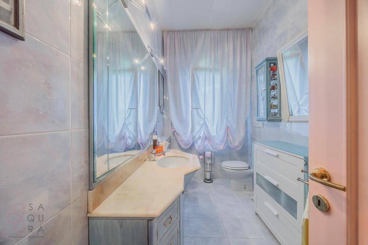 Funktionales Badezimmer mit hellen Fliesen, Einzelwaschbecken und einem Spiegelschrank.