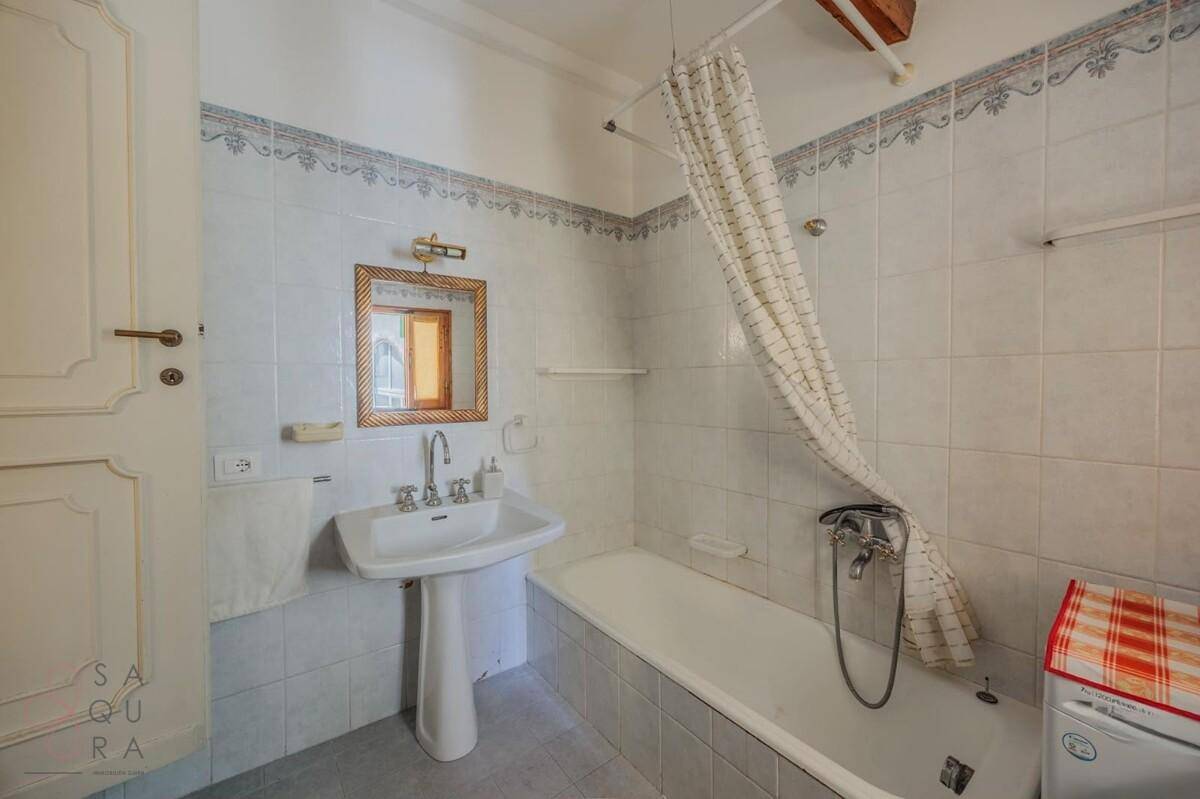 Badezimmer mit Badewanne, Standwaschbecken und weiß-blauen Fliesen.