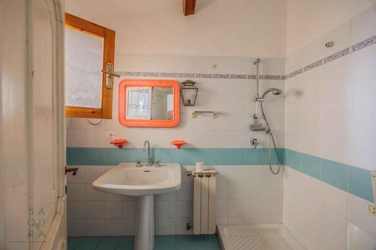 Badezimmer mit Dusche, Standwaschbecken und farbigen Akzenten an den Fliesen.