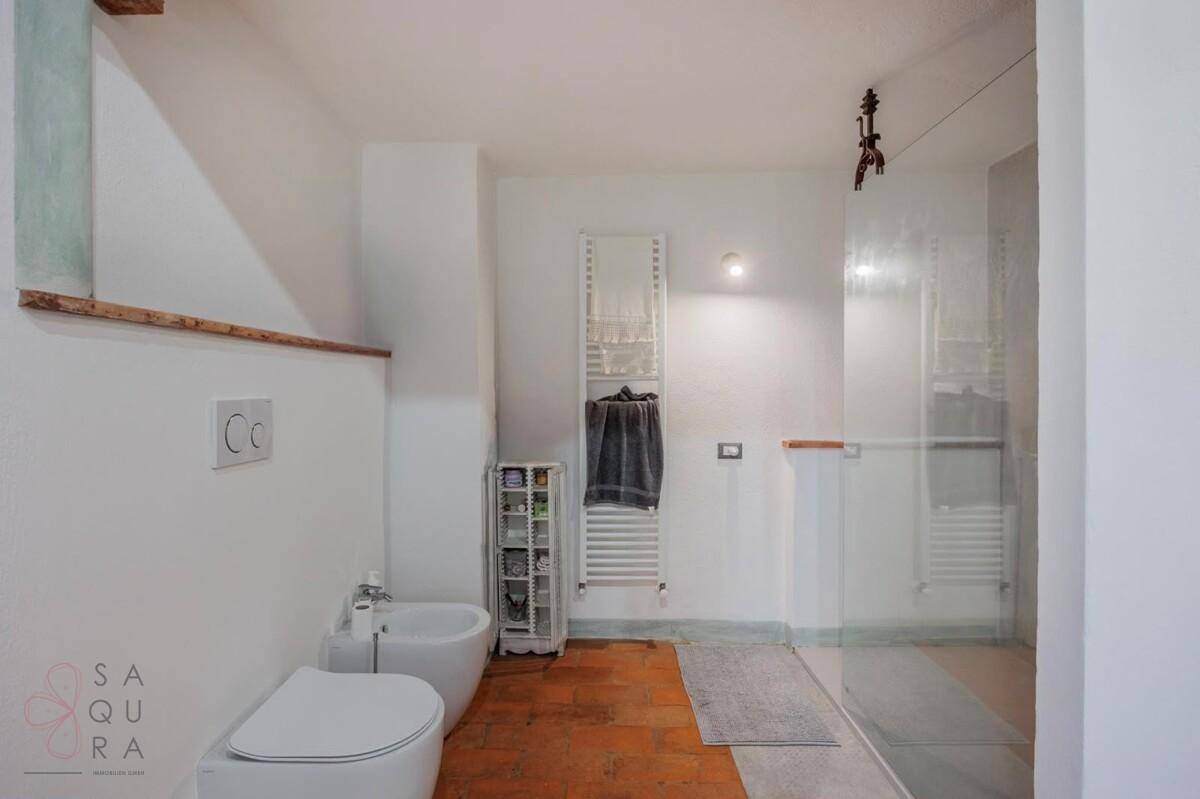 Modernes Badezimmer mit Dusche, Bidet, WC und beheiztem Handtuchhalter.